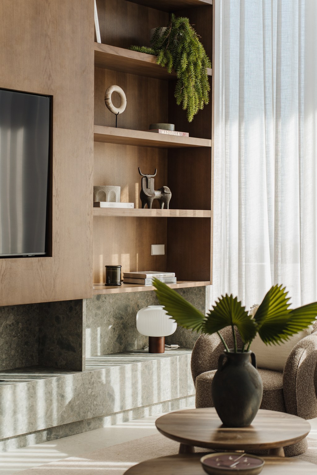 Oak media wall with shelving, terrazzo hearth and sheer linen curtains