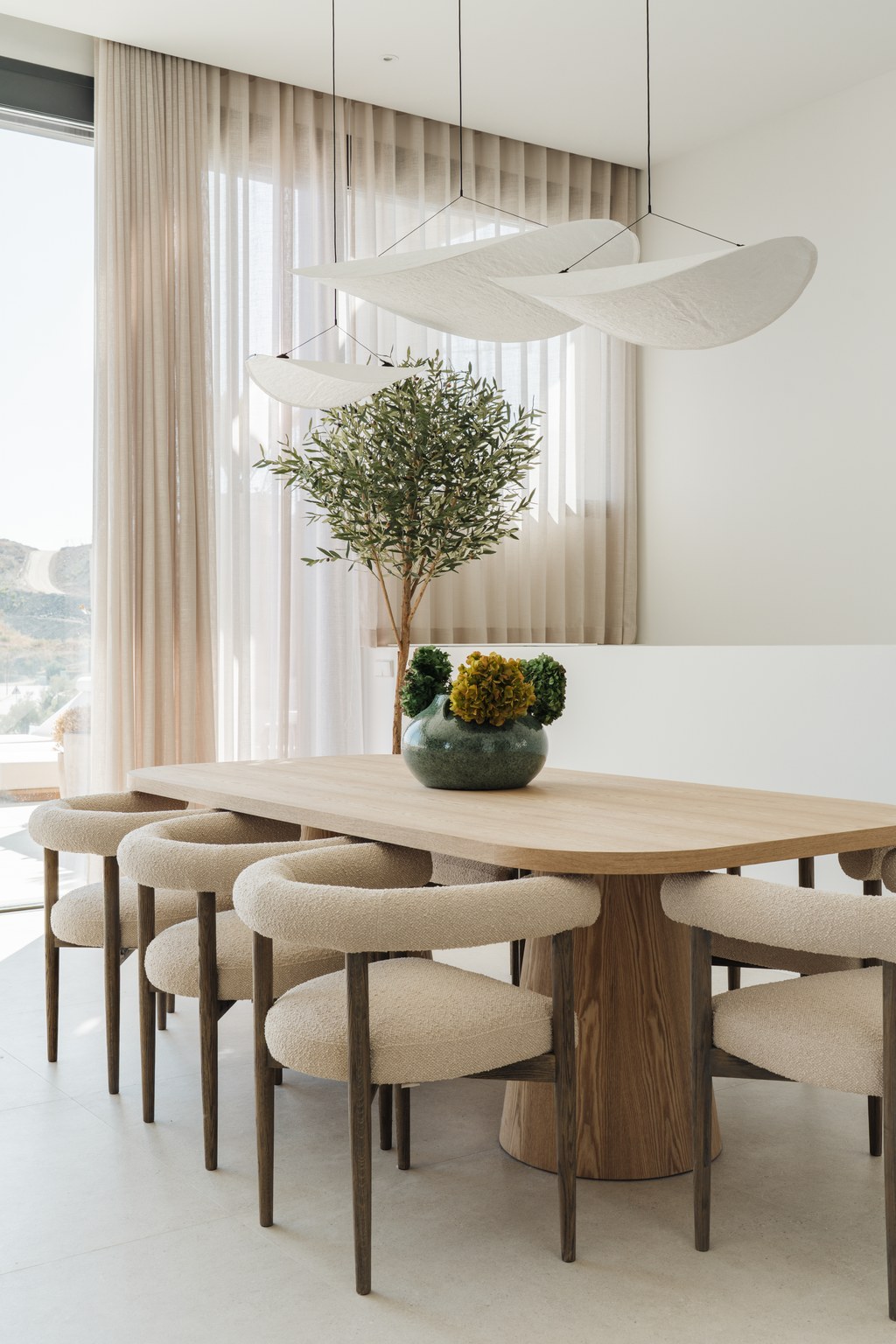 Oak dining table beneath sculptural pendants