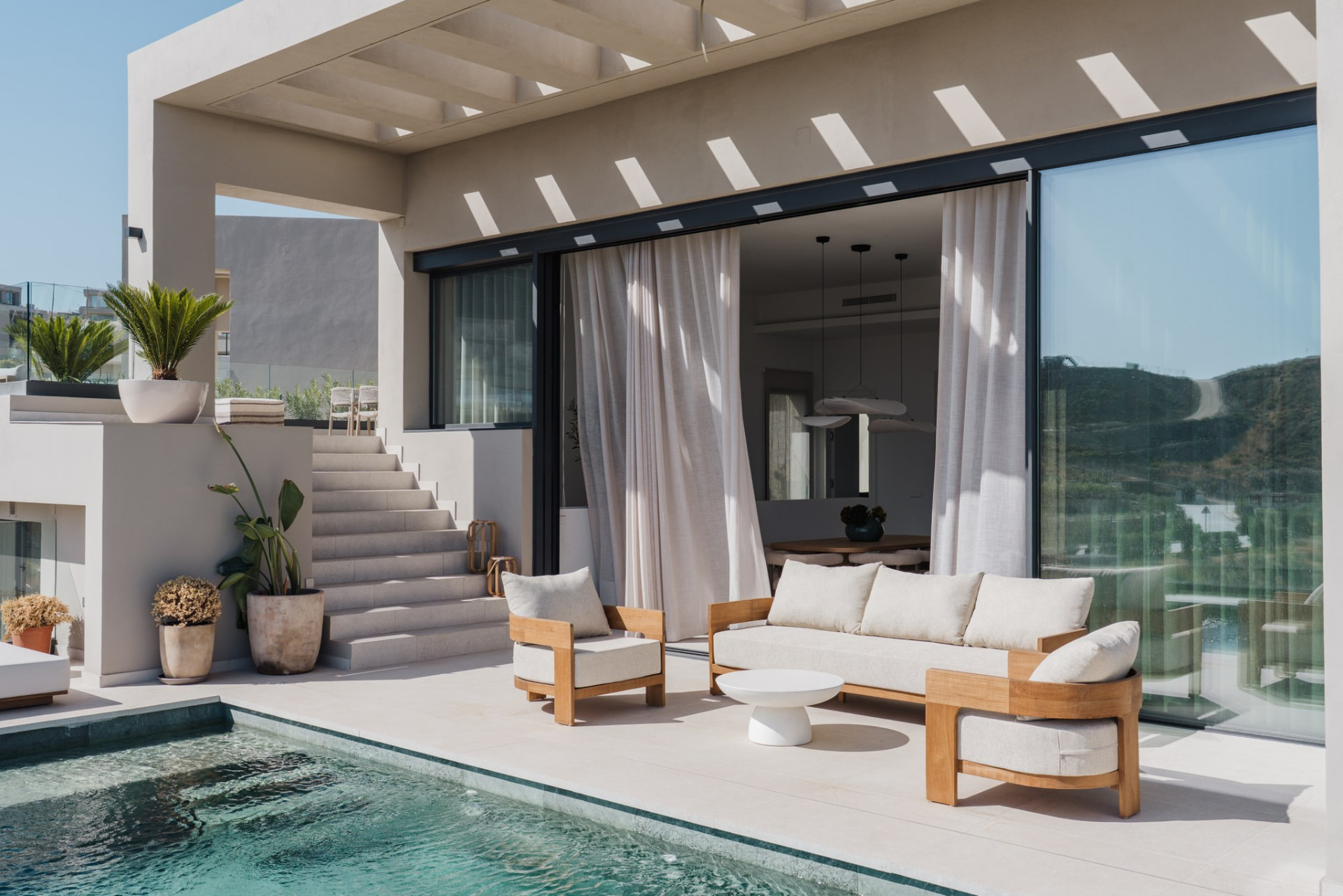 Covered pool terrace with teak lounge furniture and open sliding doors